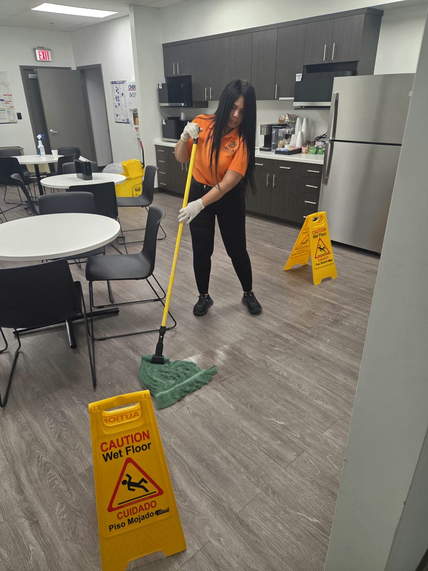 INGAL SERVICES INC employee damp mopping a breakroom floor with wet floor caution signs in place