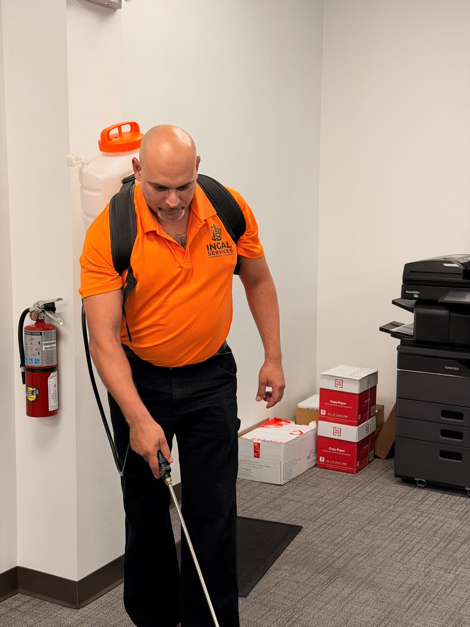 INGAL SERVICES INC employee applying disinfectant with a backpack sprayer in a copy room