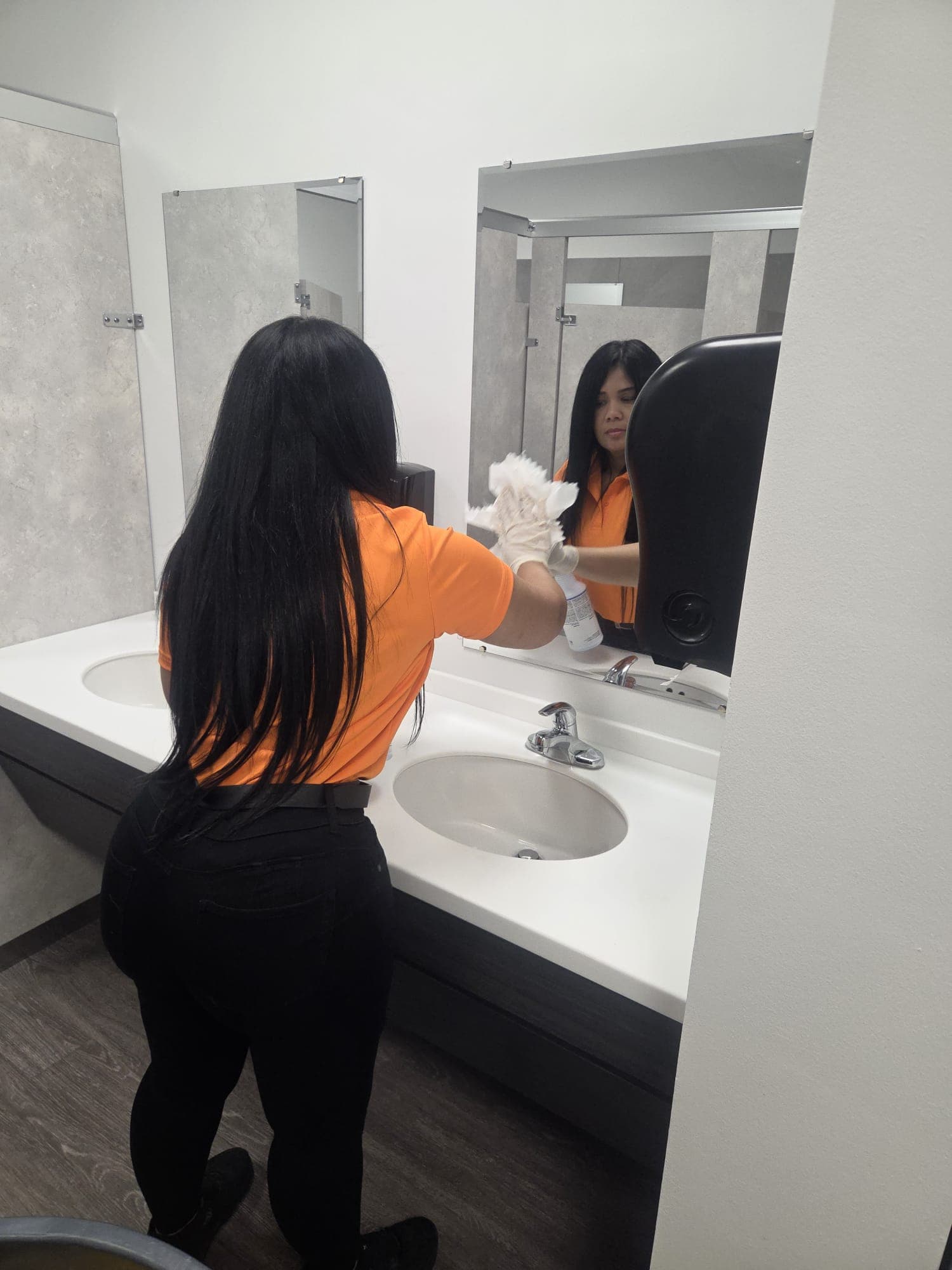 INGAL SERVICES INC employee polishing a restroom mirror streak free