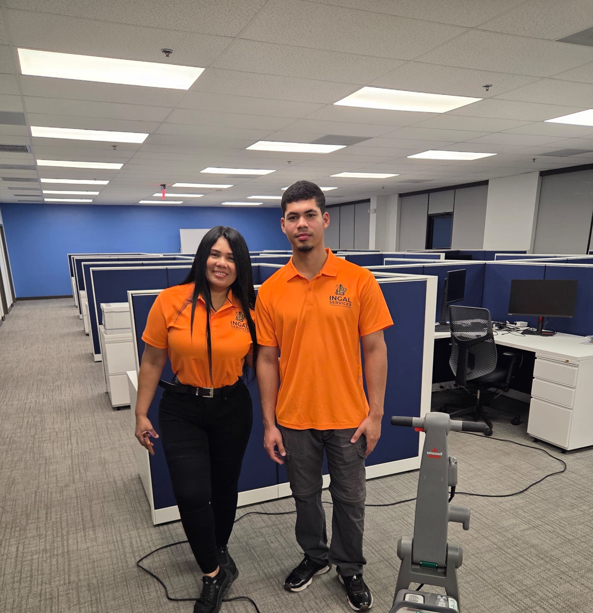 Two INGAL SERVICES INC employees in orange uniforms standing in a client office after an evening clean