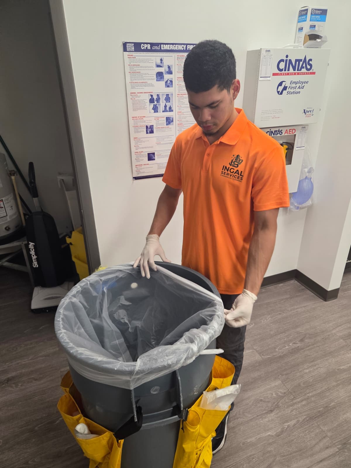 INGAL SERVICES INC employee fitting a fresh liner to a barrel cart beside a first aid station