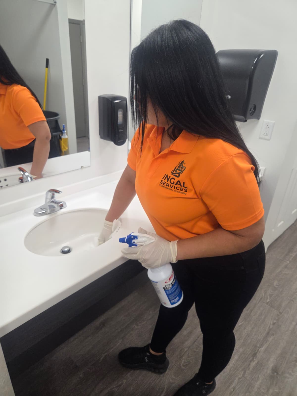INGAL SERVICES INC employee sanitizing a restroom vanity and sink basin